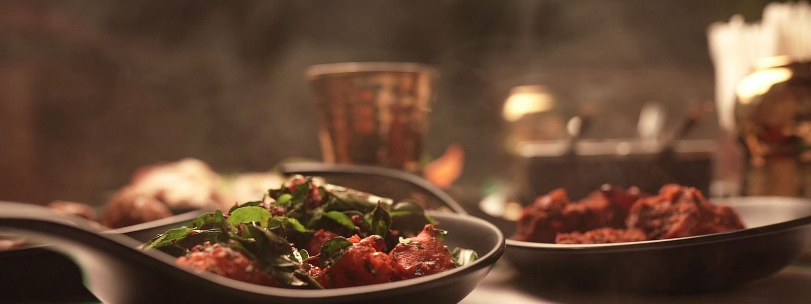 An image of a chicken fry seasoned with curry leaves served in a pan - Pai Group of Hotels