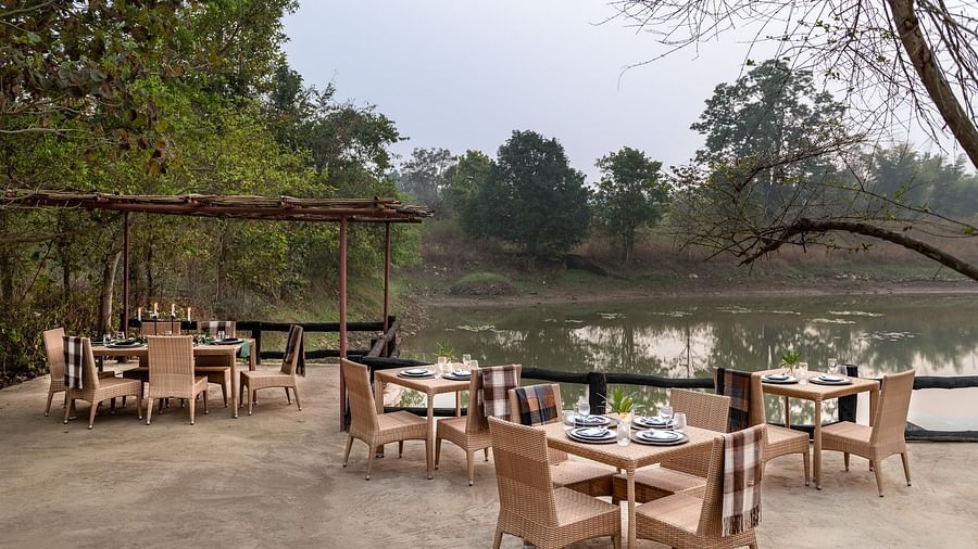 Multiple tables and chairs with a lake view at Swimming Pool at Saccharum Safari Lodge, Balaghat