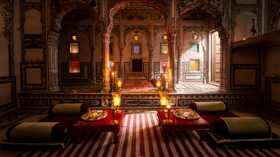 A richly decorated lounge at Fort Barli, featuring ornate arches, warm lighting, and plush seating, exudes a sense of historical grandeur and intimate ambience.