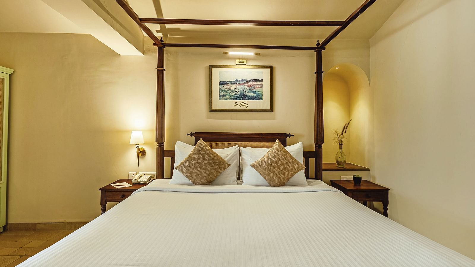 Warmly lit bedroom at Mango Hill Shola, Ooty with a neatly made double bed, side tables, and framed wall art.