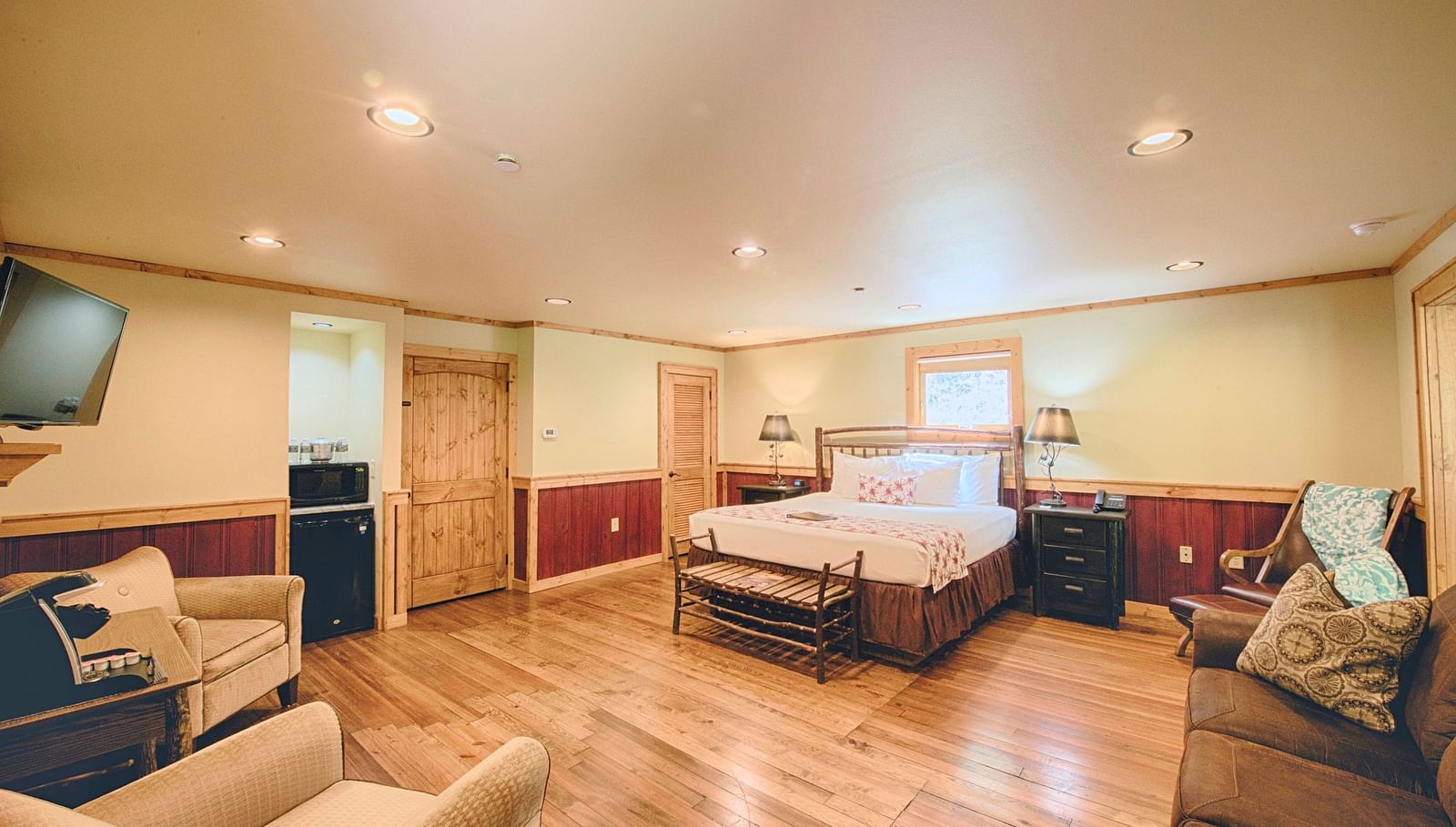 corner view image of a bedroom featuring a plush double bed in the middle and a seating area opposite to it - Historic Tapoco Lodge