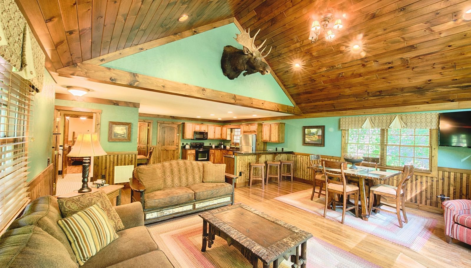 full view image of the living area with pastel green colored walls complemented by a decorative stag head - Historic Tapoco Lodge