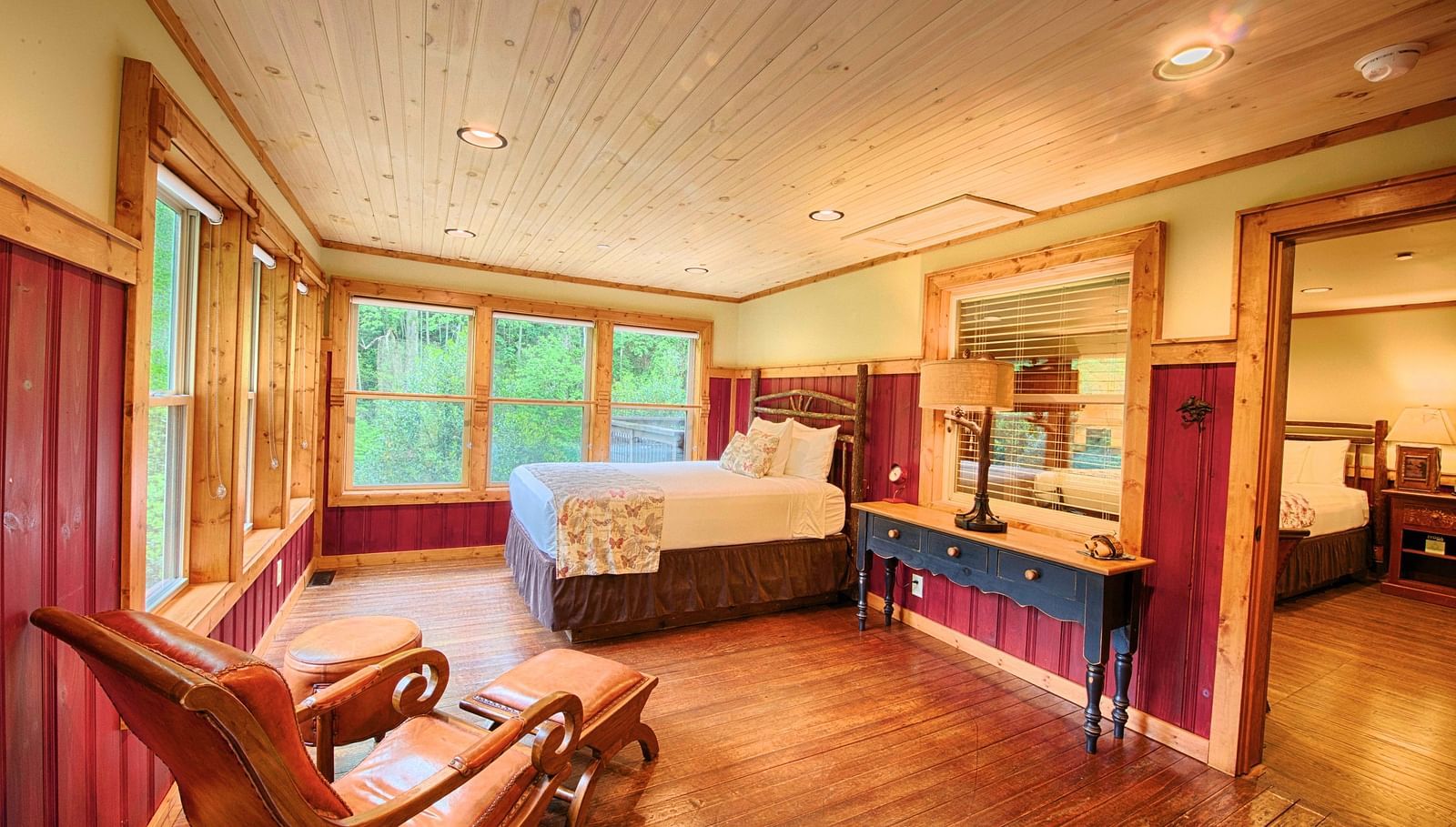 side view image of a bedroom featuring a double bed along with a cushioned armchair and a huge mirror besides it - Historic Tapoco Lodge