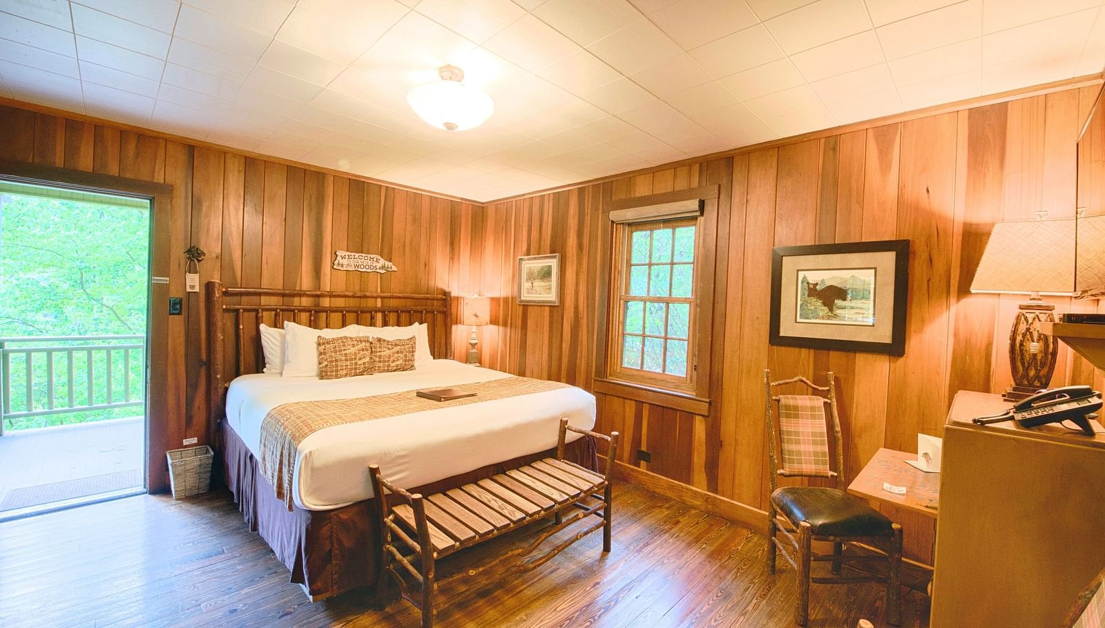 full view image of the a bedroom with a couple bed along with a small seating are in front of the bed - Historic Tapoco Lodge