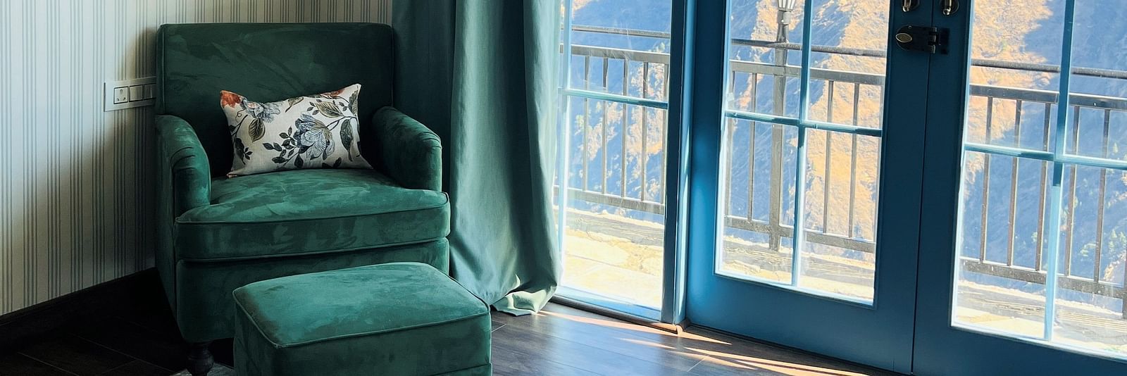 Image of a sofa in the corver of the room by the large French window | Faraway Cottages, Auli