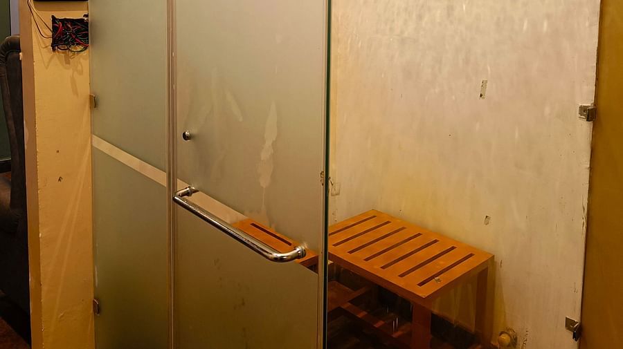Glass-panelled room at DLS Forest Vines Resort featuring a wooden stool inside.