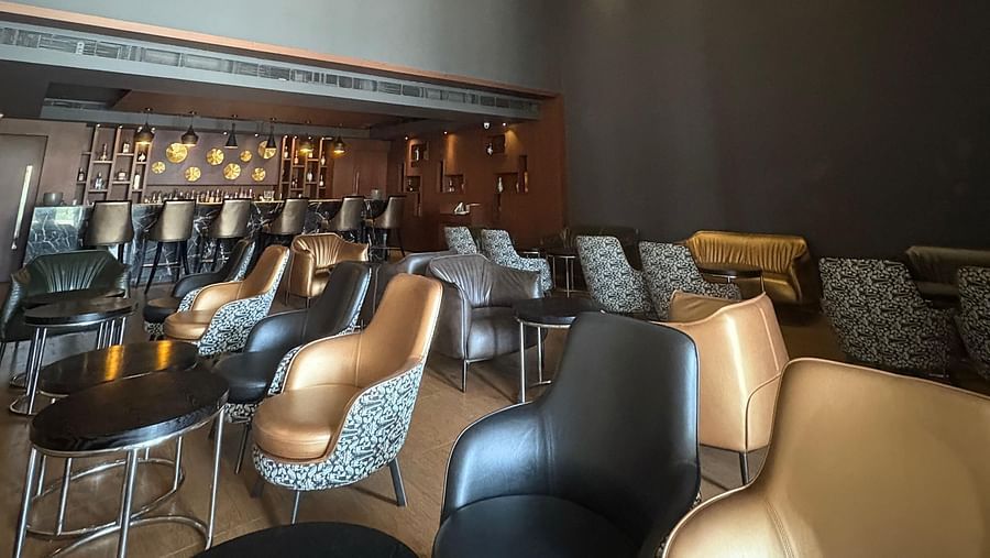 A wide shot of a bar with a geometric chandelier, showcasing the space and seating from a different perspective.