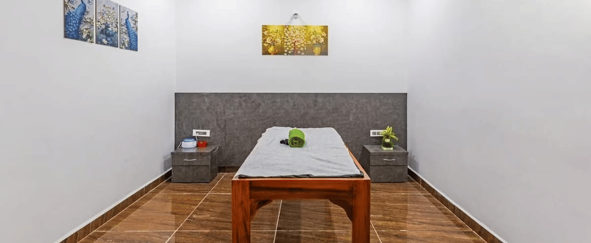 Minimalist spa room with a wooden table and decorative wall art at Siri Ambari Resorts and Spa.