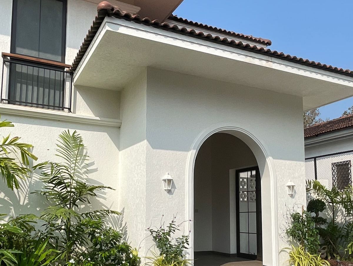 The exterior of a beautiful villa featuring an arched entrance, black balcony railing, and a cobblestone pathway - BluSalzz Villas - Alocassia, Anjuna.