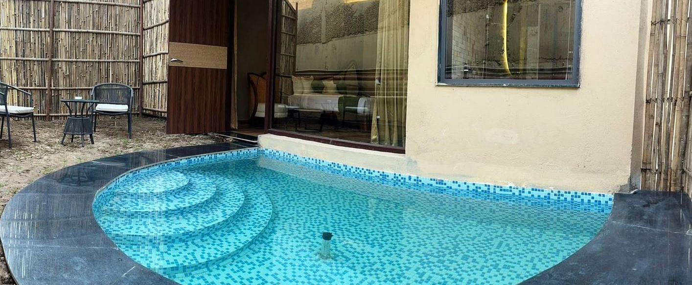 Luxury Villa with Plunge Pool featuring a private outdoor pool with steps leading into the water is surrounded by dark stone and lush greenery at The Qualia Resort Club & Brewery, Udaipur.