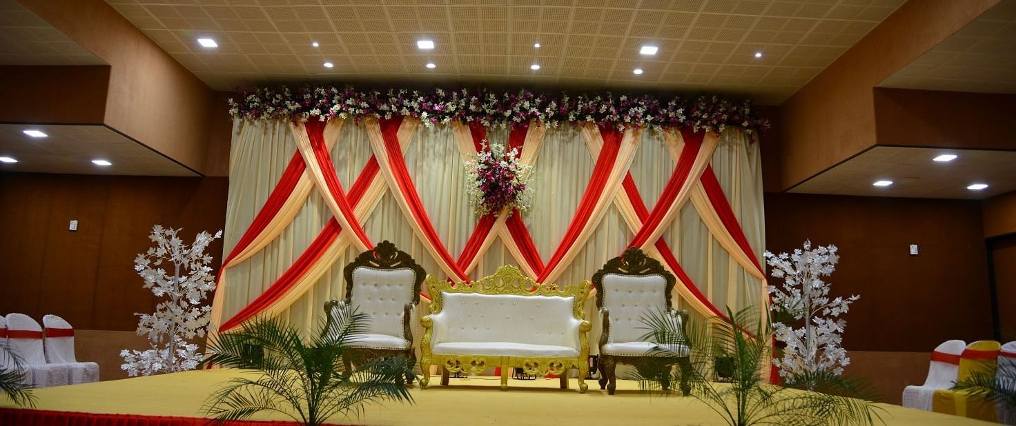 The stage of the wedding area decorated with fancy furniture, curtains, and flowers.
