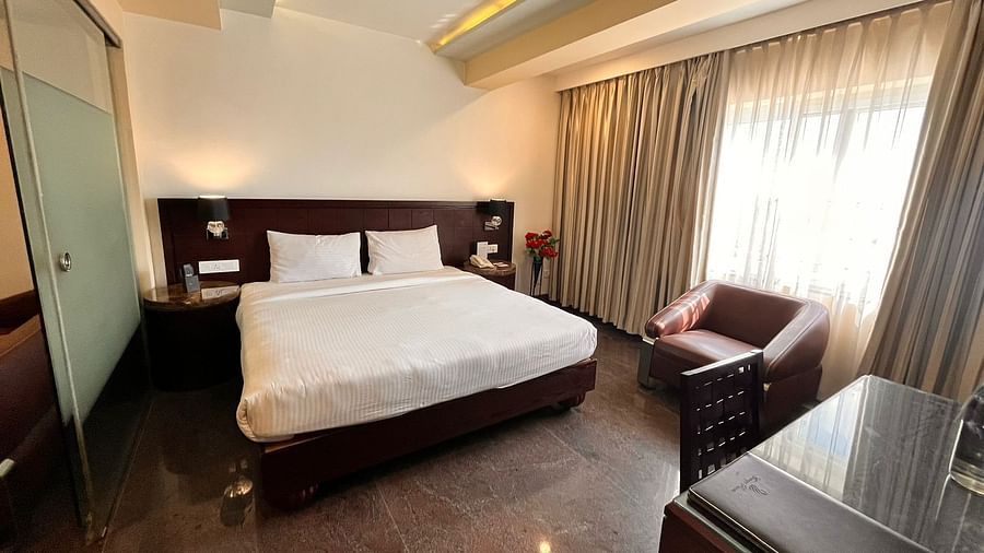 Executive suite room featuring a plush bed with nightstands attached to headboard and a couch placed next to the window