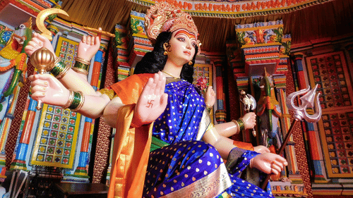An overview of an idol of goddess kali inside a temple and colourful decor on the walls