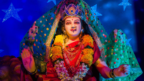 a close up image of the hindu deity durga maa with lights shining on her