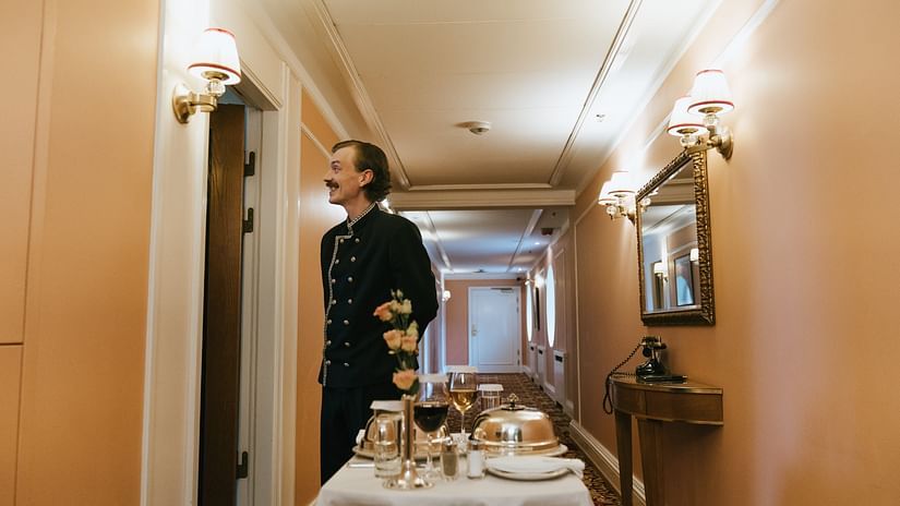 a man with room service waiting for guests outside the room