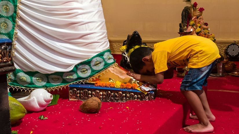 An image of a child bowing down to a statue of a hindu diety inside a temple