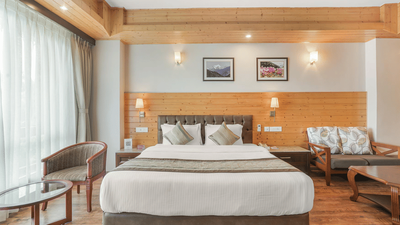 A room at Voyage Alpine Abode, with a large bed, pillows, spreads, curtains, chairs, and sofas.