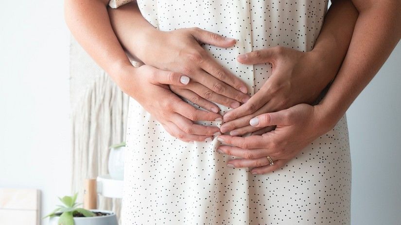 a couple standing while keeping their hands on the stomach of the soon-to-be mom