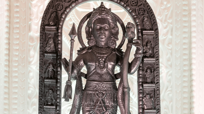 A carved wooden statue of a multi-armed deity stands inside a temple archway.