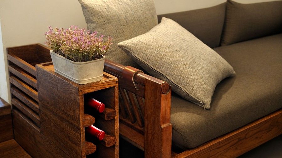 Comfortable couch with cushions and a wooden side table with a plant and books.