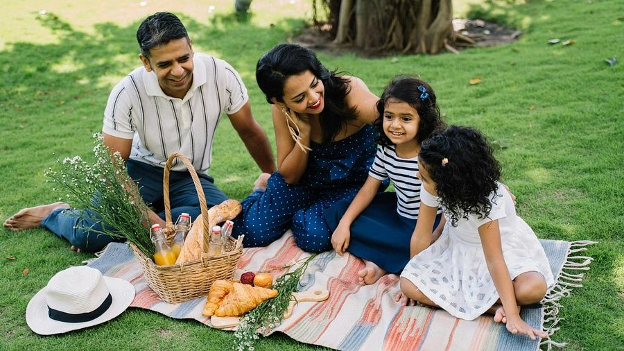 A family enjoying a picnic on a grassy lawn at a resort, with a basket of fruits and drinks—ideal for showcasing family-friendly experiences.