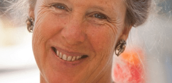 A smiling woman wearing a necklace, captured in natural light.