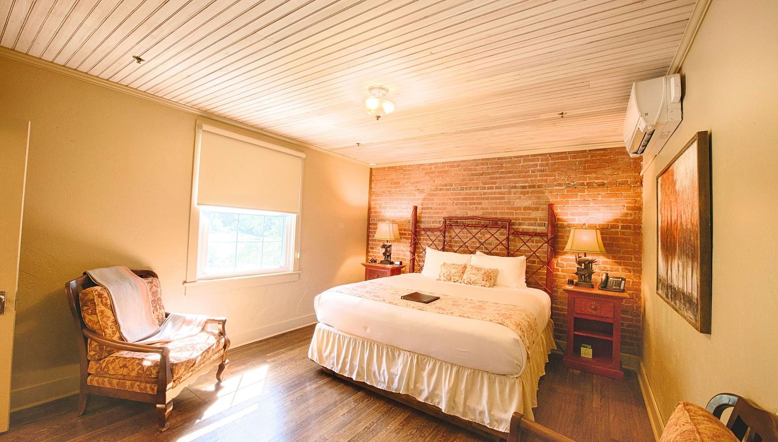 full view image of a bedroom featuring a bricked wall behind the double bed - Historic Tapoco Lodge