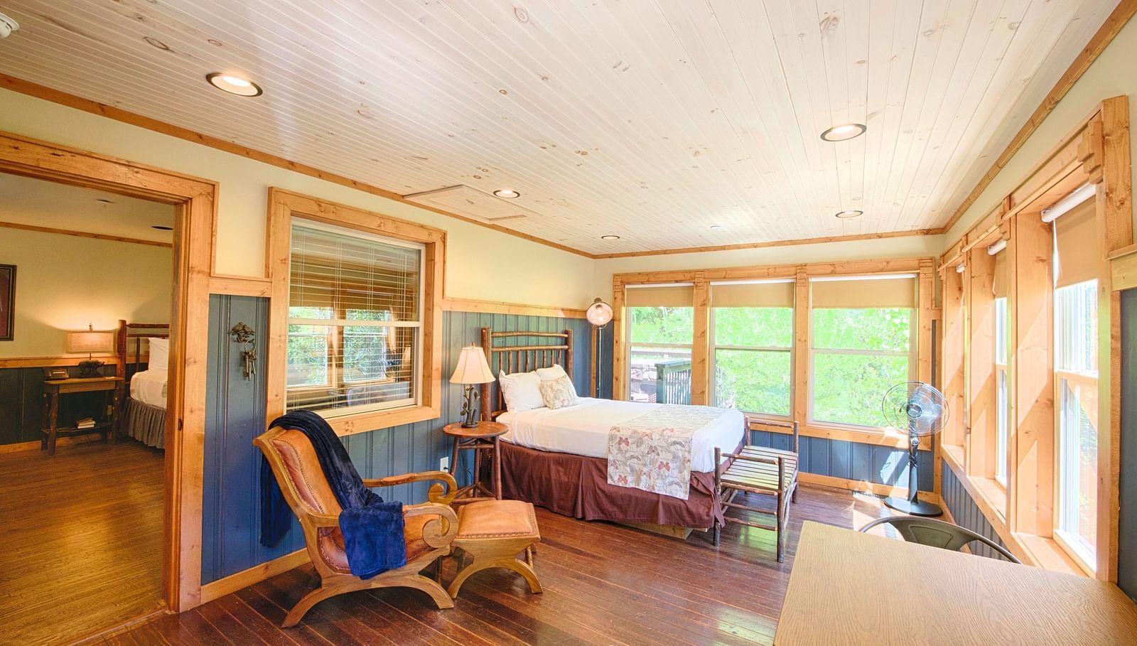 a brightly lit room with ample natural light featuring blue colored wooden panels on the wall and a double bed - Historic Tapoco Lodge