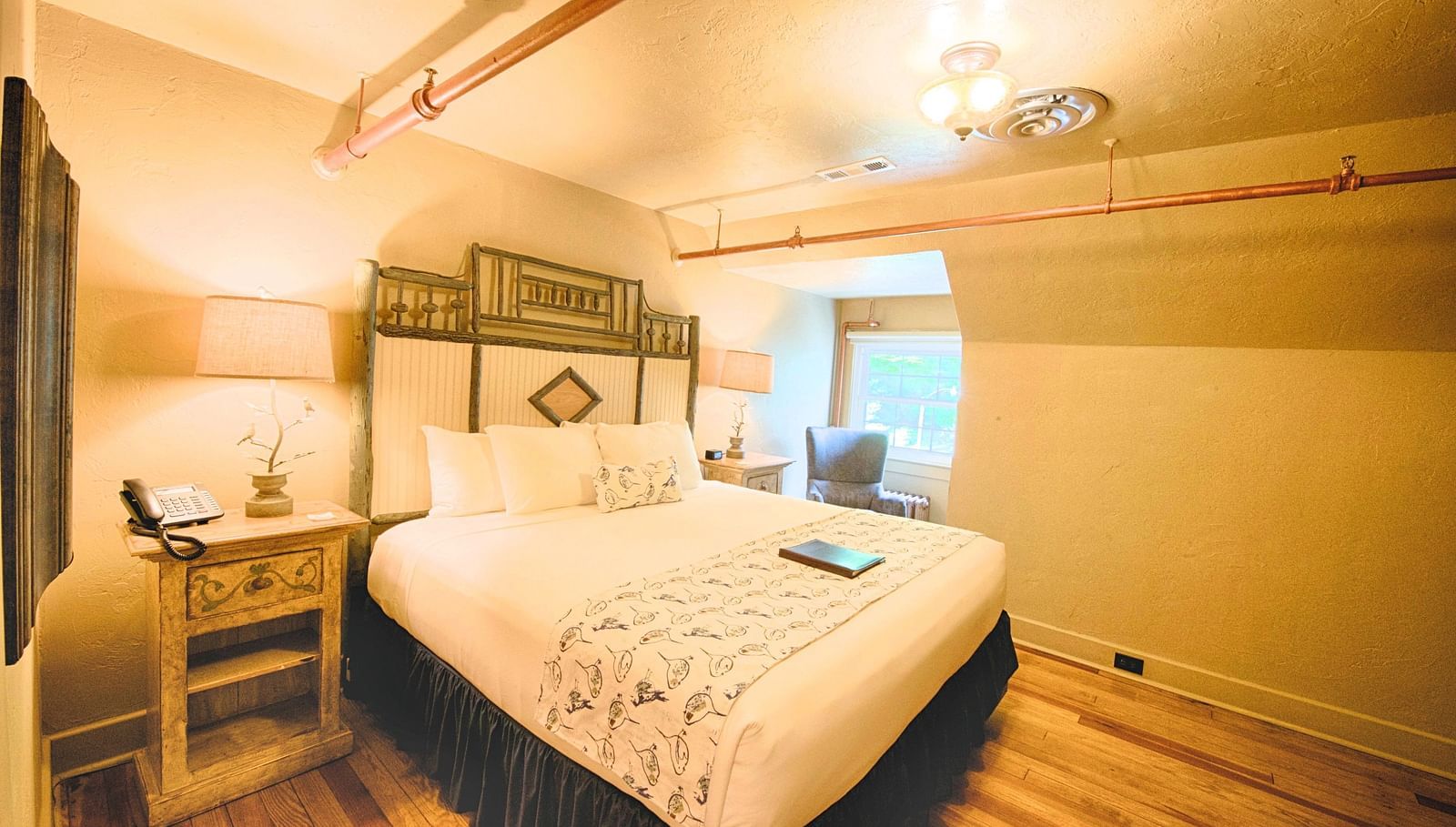 a comfortable double bed with a huge head board behind it in a warmly illuminated room - Historic Tapoco Lodge