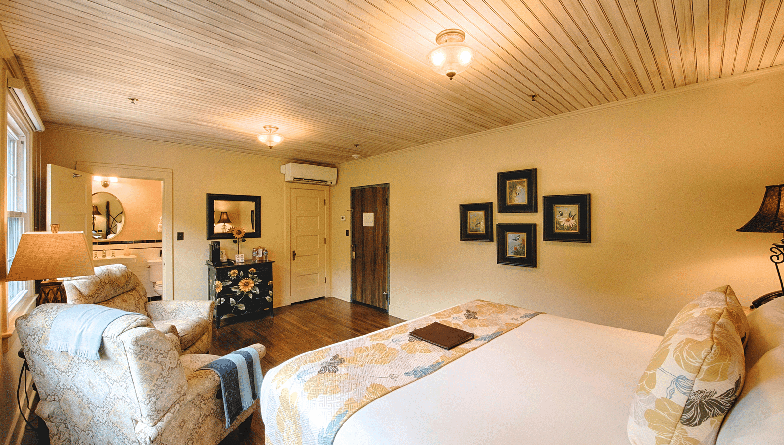 a cozy bedroom with minimalist and sleek interiors featuring a double bed and the back of a cushioned armchair - Historic Tapoco Lodge