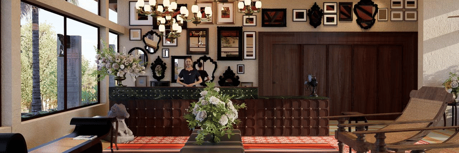 Reception lobby at MGM Paradise Resort, Kumbakonam featuring a lady behind the desk, photo frames on the wall behind her, and in front of the desk there are seating spaces like sofa chairs, benches, and centre table.