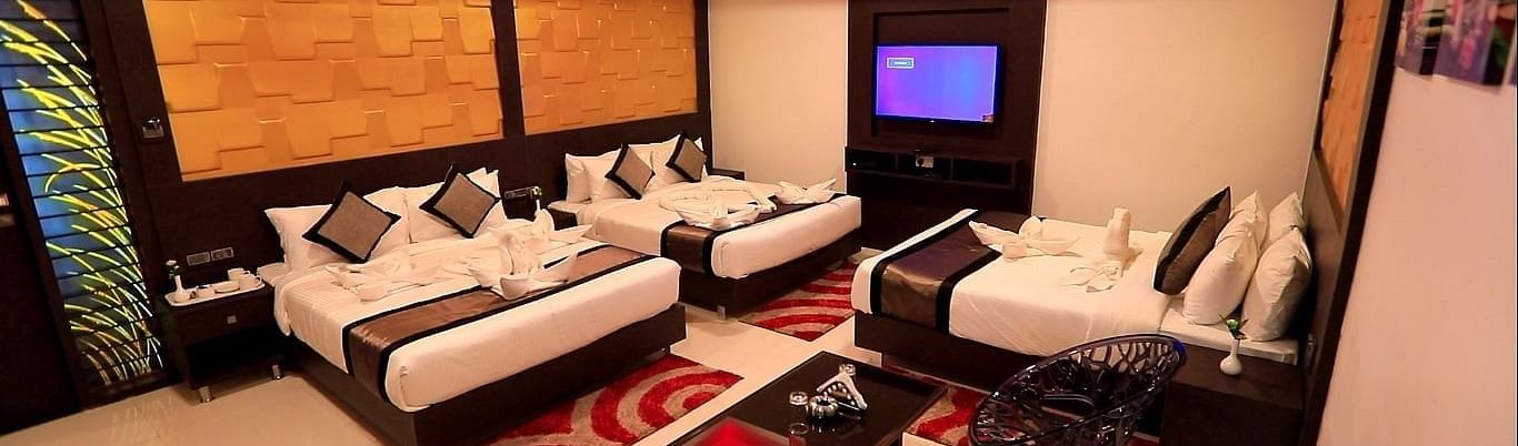A room with three beds and a sitting area on the side at Parampara Residency, Kushalnagar.