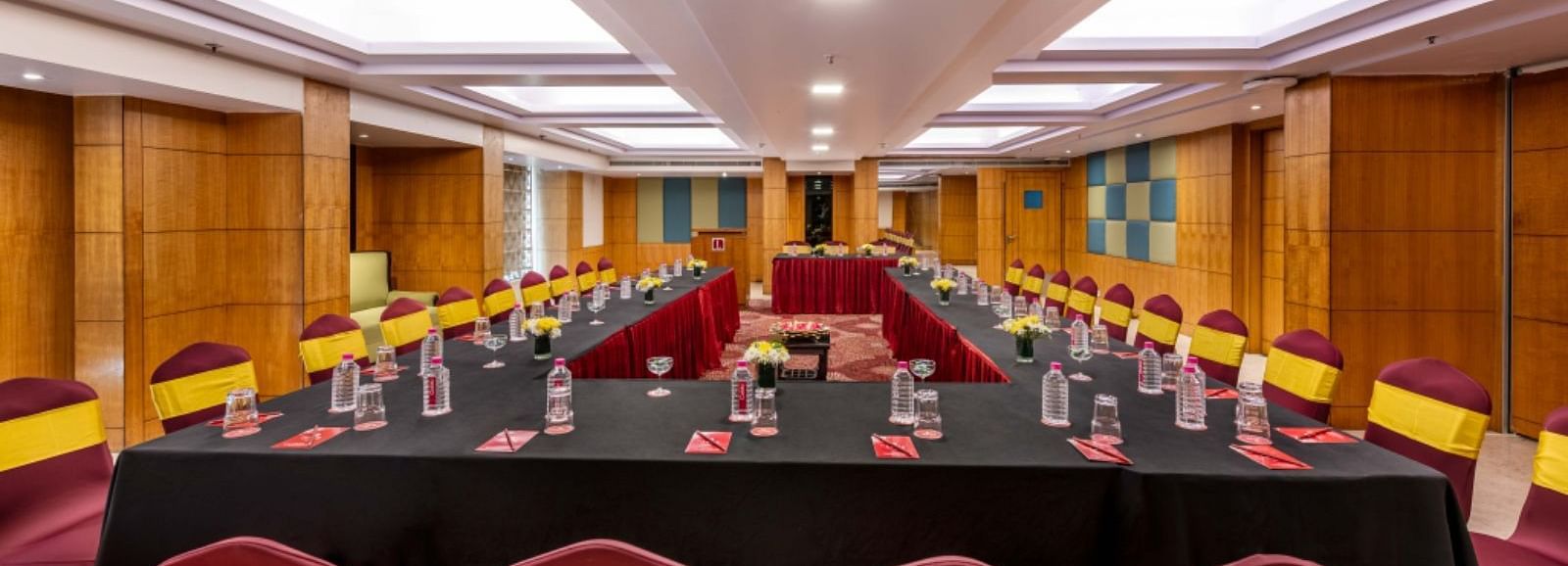 a large boardroom with U-shaped seating arrangements  with wood-panelled walls and ceiling lights at Libra Lords Inn Jaipur