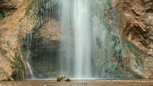 Cascading waterfall from a height and surrounded by rocks