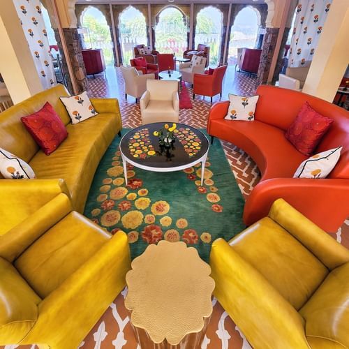 A room with curved seating, a round table, and arched doorways, viewed from above at Tijara Fort-Palace - 19th Century, Alwar.