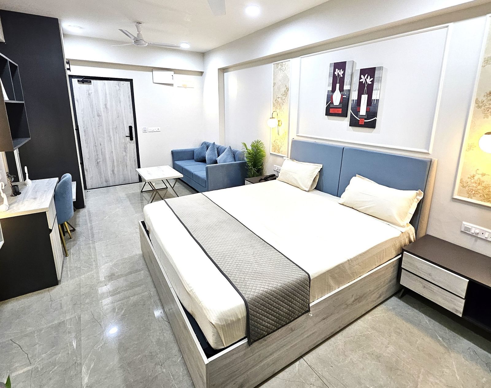 Spacious and elegantly designed serviced apartment in Jaipur featuring a plush bed with a soft headboard, a cosy seating area with a modern sofa, a sleek work desk, and stylish décor - Urban Suites by BluSalzz, Jaipur