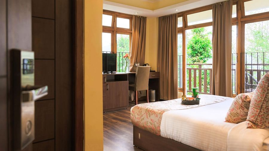 the premier room with balcony at Yashshree Karbari Resort & Spa, Yangang taken from the entrance door of the room with beautiful lush green views from the balcony