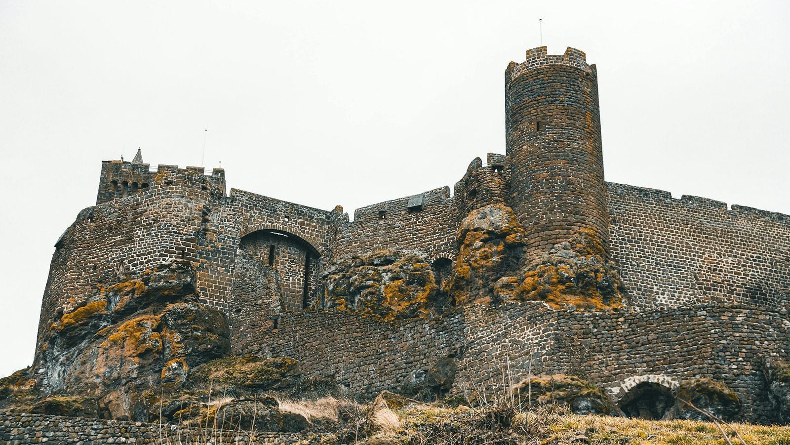 Ruins of an old stone fort with rugged walls and patches of greenery.