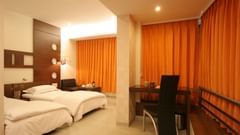 Well-lit Executive Rooms in Pride Biznotel Alkapuri featuring plush beds and a work desk at a distance