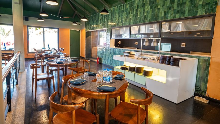 Dining area and counter at Song of the Sea restaurant with wooden seating and green interior.
