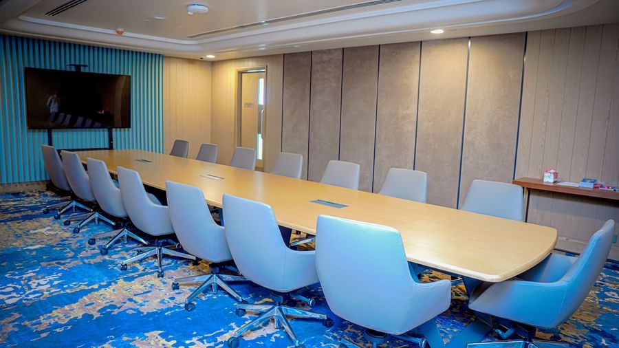 A meeting room in Hargeisa with a long table, ergonomic chairs, and a television - Serene Sarovar Premiere Hargeisa