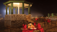 A spacious outdoor deck with seating and dining tables, surrounded by lush trees, at Polo Cherrapunjee Resort.