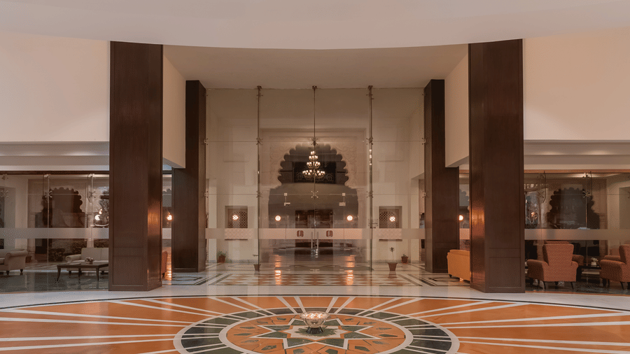 An interior spacious hall at Shri Vallabh Vilas Lords Plaza Nathdwara, featuring circular patterned floor design, tall pillars, and a reception area in the background.
