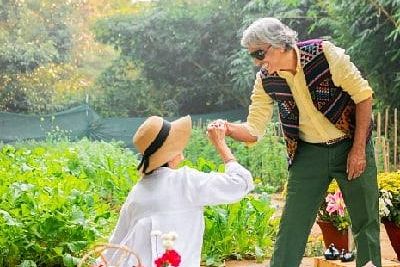Staff member serving food to a seated guest in the garden area of Karma Chalets during daylight.
