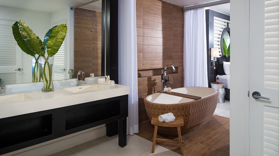 A hotel bathroom with a bathtub and a flower vase with a plant placed on the sink - S Hotel Montego Bay, Jamaica