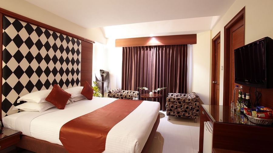 A well-appointed room with a patterned accent wall, cosy bedding, and contemporary furnishings for a comfortable stay - The President Hotel Jayanagar, Bangalore