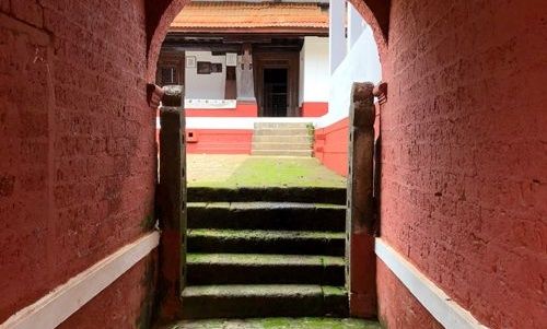 Red archway leading to stone steps and a courtyard.