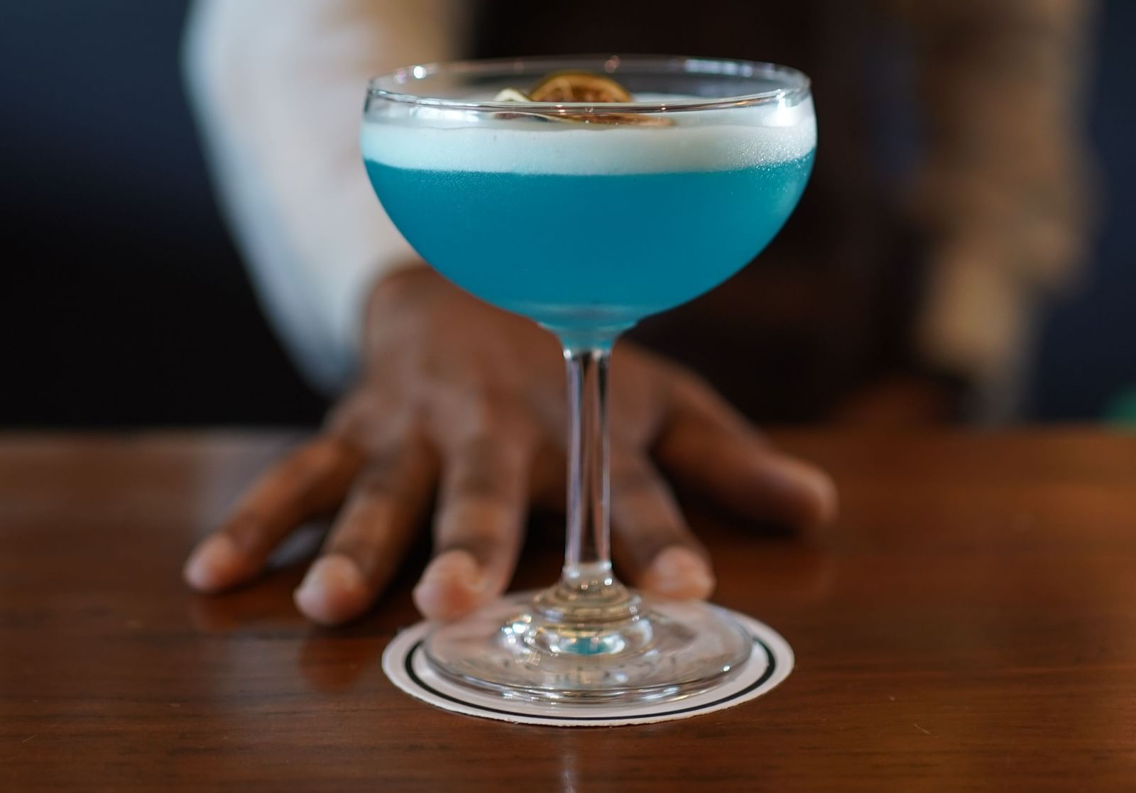 A bartender serving a vibrant blue cocktail in focus - Polo Hotel Agartala