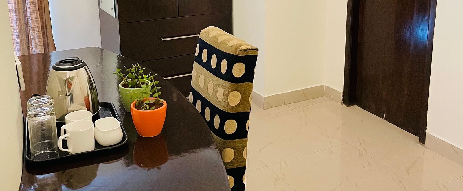 A glimpse into a hallway with a dark table and closed wooden doors at Sanctum Suites Domlur, Bangalore.