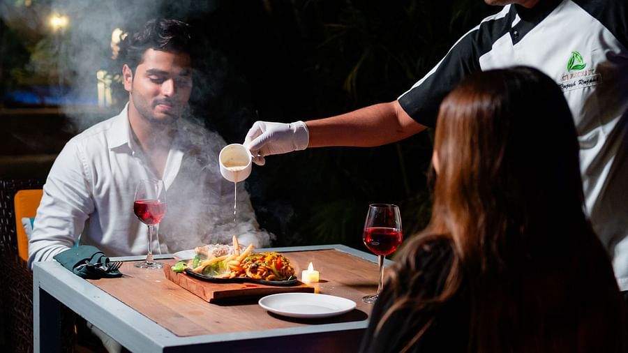 A couple being served by a chef at the poolside, relishing a charming dining experience at Crescent Spa & Resort, Indore